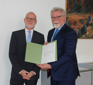 Foto von Justizminister Herbert Mertin und Herr Mario Mannweiler mit einer Urkunde in der Hand