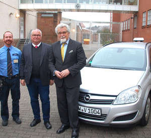 Gruppenfoto von Gabriele Graf, Daniel Riegel, Jürgen Buchholz und Justizminister Herbert Mertin vor einem Fahrschulauto der JVA